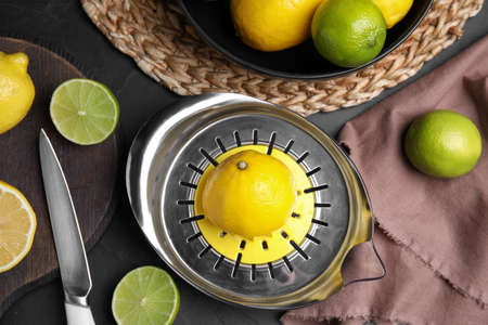 Squeezer, fresh lemons and limes on black table, flat layの写真素材