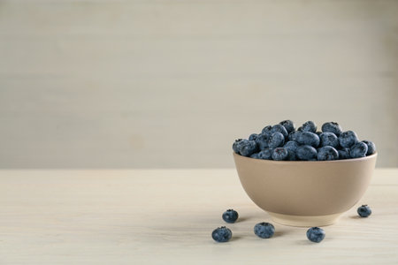 Ceramic bowl with blueberries on light wooden table, space for text. Cooking utensilの写真素材