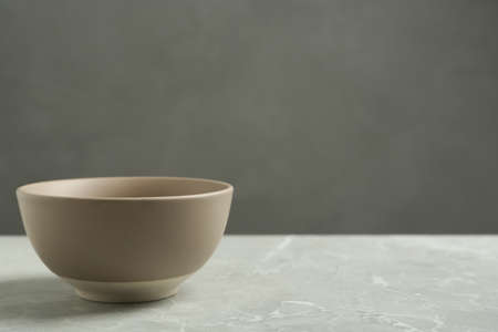 Stylish empty ceramic bowl on gray table, space for text. Cooking utensilの写真素材