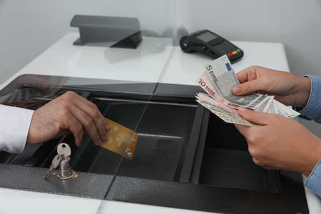 Woman putting money on card in bank, closeup. Currency exchangeの写真素材