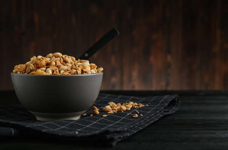 Ceramic bowl with granola on black wooden table, space for text. Cooking utensilの写真素材