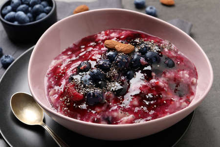 Tasty oatmeal porridge with toppings on gray table, closeupの写真素材