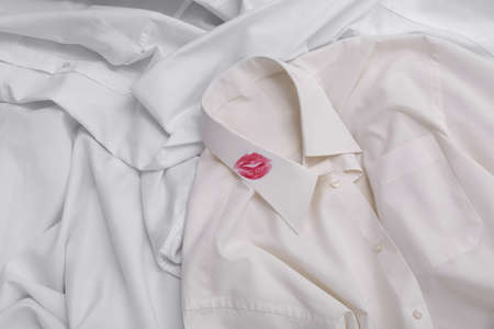 Men's shirt with lipstick kiss mark among other clothes as backgroundの写真素材