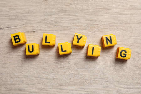 Word Bullying made of yellow cubes with letters on wooden table, flat layの写真素材
