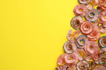 Many colorful pencil shavings on yellow background, flat lay. Space for textの写真素材