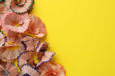 Many colorful pencil shavings on yellow background, flat lay. Space for textの写真素材