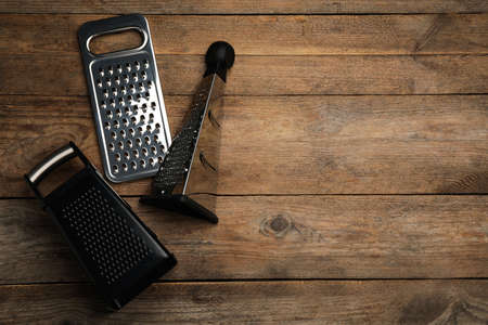 Different modern graters on wooden table, flat lay. Space for textの写真素材