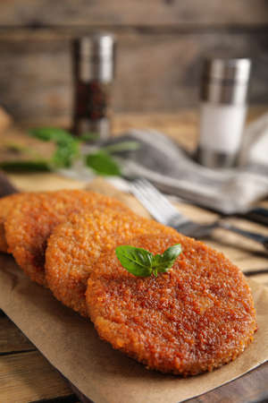 Delicious fried breaded cutlets with basil on wooden tableの写真素材