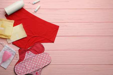 Women's underwear, cloth menstrual pad and other female hygiene products on pink wooden table, flat lay. Space for textの写真素材