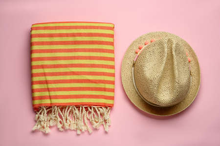 Beach towel and straw hat on pink background, flat layの写真素材