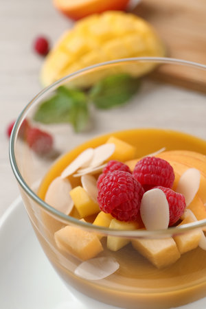 Delicious panna cotta with mango coulis, fresh fruit pieces and almond flakes in bowl, closeupの写真素材