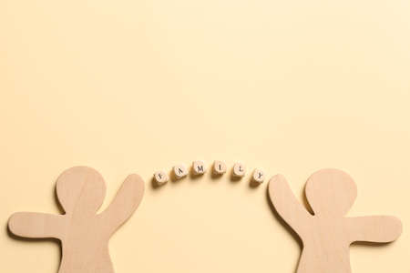Wooden figures joined by word Family made of cubes with letters on pale yellow background, flat lay....