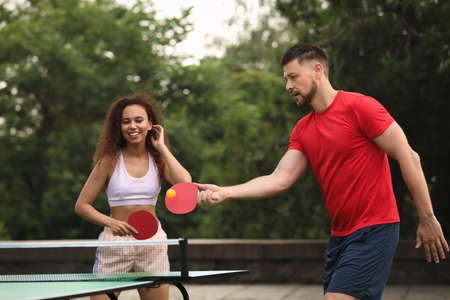 Friends playing tennis table outdoors on summer dayの写真素材