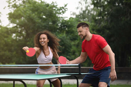Friends playing tennis table outdoors on summer dayの写真素材