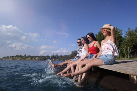 Group of friends having fun near river at summer party