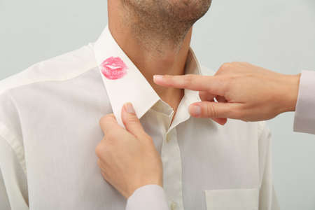 Woman pointing at lipstick kiss mark on her husband's shirt, closeupの写真素材