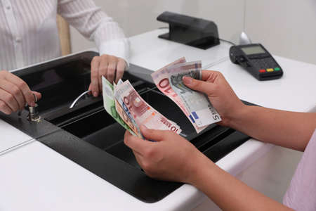 Woman with money at cash department window, closeup. Currency exchange