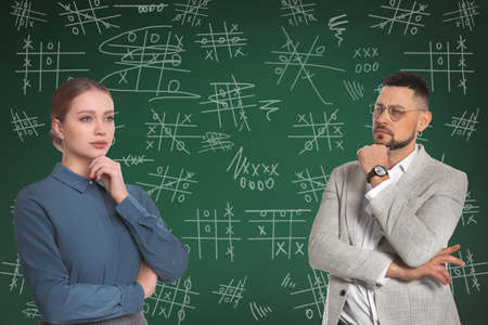 Businesspeople near green chalkboard with drawn tic tac toe game
