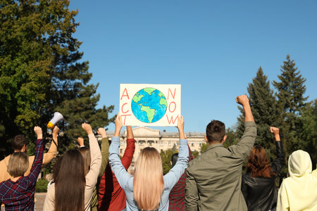 Group of people with posters protesting against climate change outdoors, back viewの写真素材