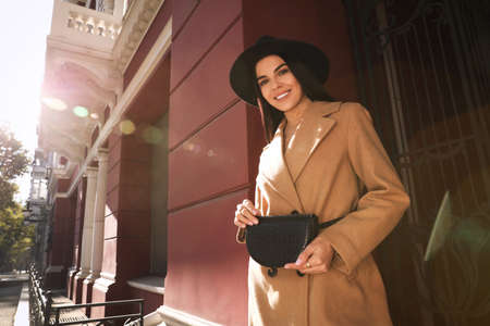 Beautiful young woman with stylish waist bag on city street, space for text