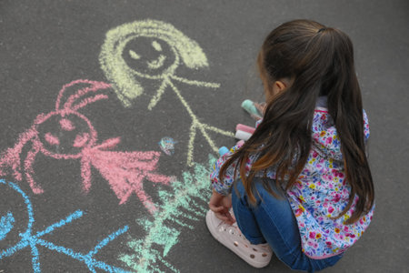 Child drawing family with chalk on asphaltの写真素材