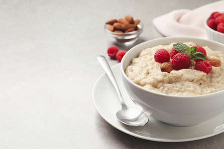 Tasty oatmeal porridge with raspberries and almond nuts served on light table, space for textの写真素材
