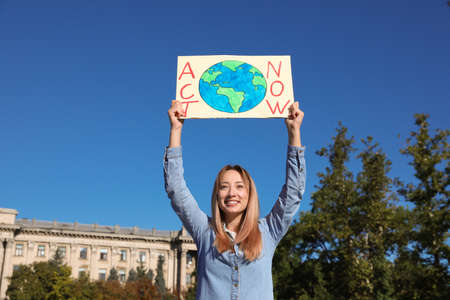 Young woman with poster protesting against climate change outdoorsの写真素材