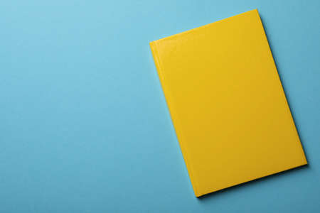 New yellow planner on light blue background, top view. Space for text