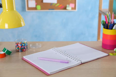 Notebook and pen on wooden desk in roomの写真素材