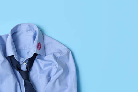 Men's shirt with lipstick kiss mark and necktie on light blue background, top view. Space for textの写真素材