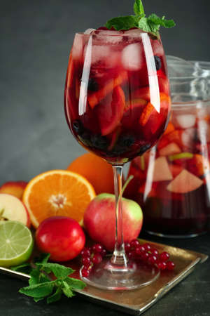 Glass and jug of Red Sangria with fruits on black tableの写真素材