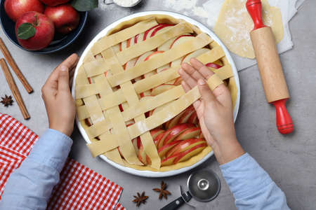 Woman decorating raw apple pie at gray table, top viewの写真素材