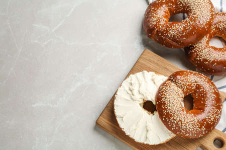 Delicious bagel with cream cheese on light table, flat lay. Space for textの写真素材