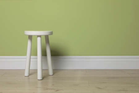 Stylish white stool near light green wall indoors. Space for textの写真素材
