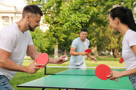 Friends playing tennis table outdoors on summer dayの写真素材