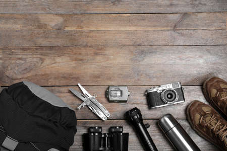 Flat lay composition with tourist backpack and other camping equipment on wooden background, space for textの写真素材