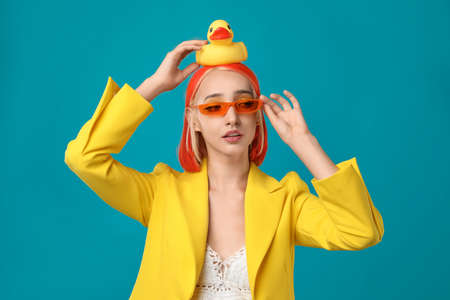 Beautiful young woman with bright dyed hair and toy duck on turquoise backgroundの写真素材