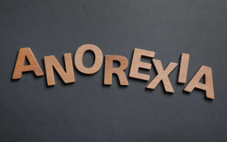 Word Anorexia made of wooden letters on dark gray background, flat layの写真素材