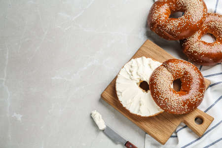 Delicious bagel with cream cheese on light table, flat lay. Space for textの写真素材