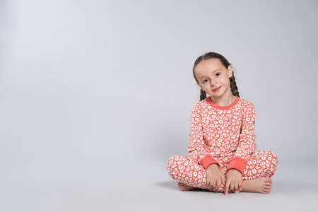 Cute girl in pajamas with floral pattern on light gray background. Space for textの写真素材