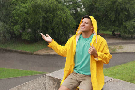 Man with raincoat walking under rain in parkの写真素材