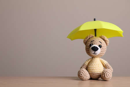 Small umbrella and toy bear on wooden table. Space for textの写真素材