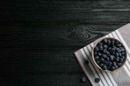 Ceramic bowl with blueberries on black wooden table, flat lay and space for text. Cooking utensilの写真素材