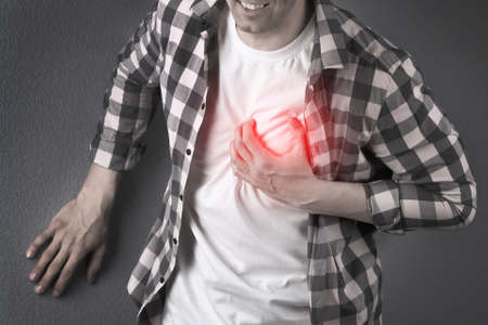 Man having heart attack on dark background, closeup viewの写真素材