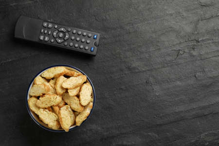 Modern tv remote control and rusks on black table, flat lay. Space for textの写真素材