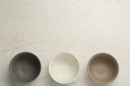 Stylish empty ceramic bowls on white wooden table, flat lay and space for text. Cooking utensilsの写真素材
