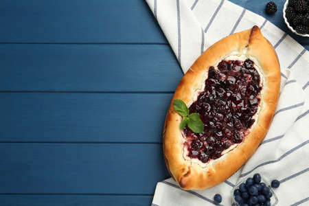 Delicious sweet cottage cheese pastry with cherry jam on blue wooden table, flat lay. Space for textの写真素材