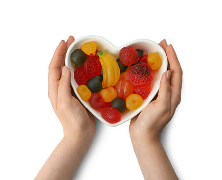 Woman holding heart shaped bowl with delicious gummy candies on white background, top viewの写真素材