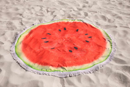 Beautiful watermelon beach towel with tassels on sandの写真素材