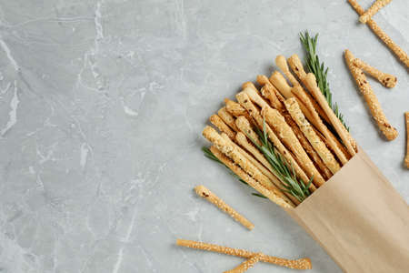 Delicious grissini sticks and rosemary on gray marble table, flat lay. Space for textの写真素材